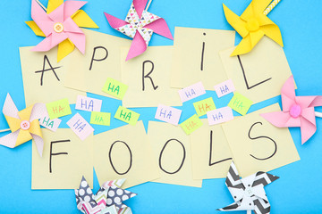 Text April Fool's Day with paper windmills on blue background