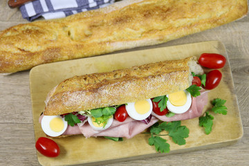 sandwich au jambon et crudités sur une planche à découper
