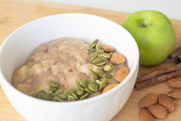 Healthy breakfast option: porridge oatmeal with cinnamon, apple and banana with almonds and pumpkin seeds sprinkled on top