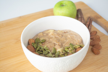 Healthy breakfast option: porridge oatmeal with cinnamon, apple and banana with almonds and pumpkin seeds sprinkled on top
