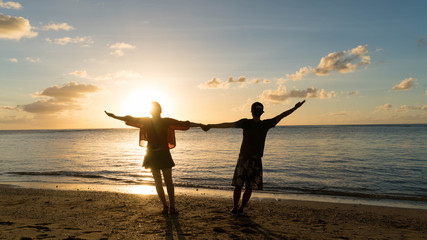 Fototapeta premium Couple kissing on the beach with a beautiful sunset in background, man lifting the woman