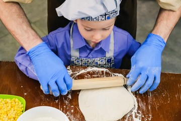 Kid in chef hat cooking pizza italian,  hands child.