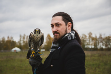 The concept of falconry. A man of European appearance with a leather glove and a beautiful Falcon...