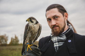 The concept of falconry. A man of European appearance with a leather glove and a beautiful Falcon...