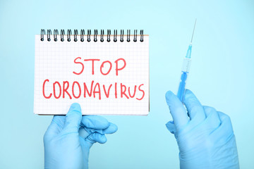 Doctor holding notepad with text Stop Coronavirus and syringe