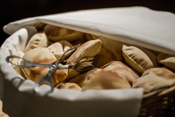 A basket of Indian bread is photographed narrowly with tongs on it.