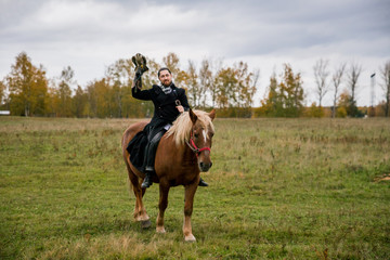 The concept of falconry. A man with a leather glove and a beautiful Falcon on handon a chestnut, red, and red horse