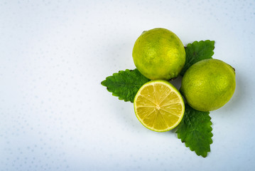 two and a half lime with green leaves on a white surface.