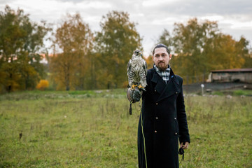 The concept of falconry. A man of European appearance with beard, with a leather glove and a...