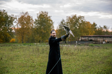 The concept of falconry. A man of European appearance with beard, with a leather glove and a...