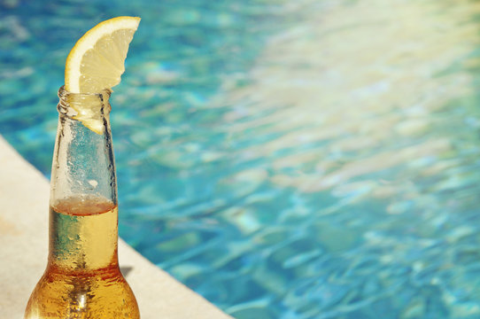 Wet bottle of beer on watter pool in the summer day