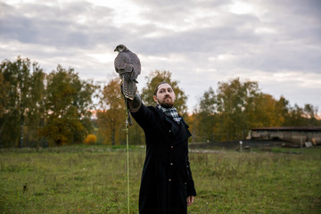 The concept of falconry. A man of European appearance with beard, with a leather glove and a...
