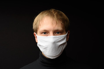 Middle aged man with medical face mask portrait close up illustrates pandemic coronavirus disease on dark background. Covid-19 outbreak contamination concept.