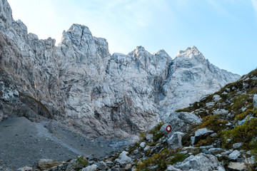 Obraz premium Sharp and rocky mountains range at Austrian-Italian border. There s a path mark on a stone. Serenity and peace. Lots of mountain ranges n the back. Lots of loose rocks, possibility of landslide