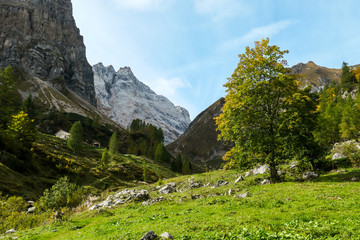 A change of the seasons in Carnic Alps, Austrian-Italian border. Sun rays coming from above the peaks. Lower parts are green, turning yellowish. Peace of mind.