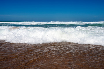 Storm on the beach. Sea waves with white foam on a sandy beach.