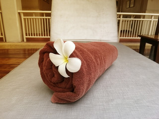 White plumeria flower and towel on a chaise longue. spa concept