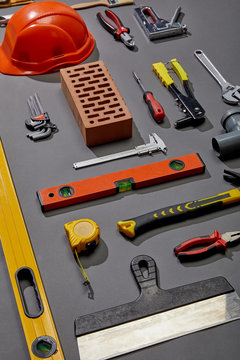 flat lay with brick, helmet and industrial tools on grey background