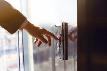 Finger presses the elevator button. Businessman pushing up elevator button. Human hand reaches for...