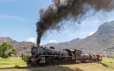 Fototapeta na wymiar Ceres, Western Cape, South Africa. December 2019. Steam engine hauling passenger coaches to the annual excursion to the Cherry Festival on Ceres golf estate. Background of Michell's Pass.