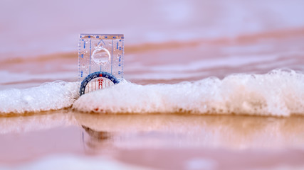 Compass on a beach washed by surf with reflections in the wet sand