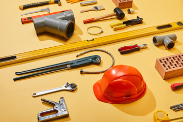 high angle view of industrial tools, helmet, bricks, measuring tape, brush, and plumbing hose on...