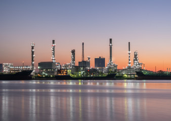 Fototapeta premium Petrochemical industry factories and oil refineries, natural gas storage tanks industry, along with the sunset sky, oil transportation by boat