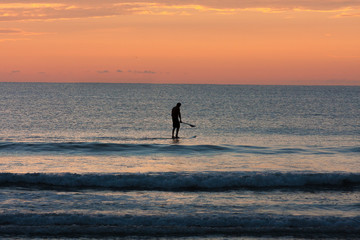 Silhouette of surfer on the beach at sunset