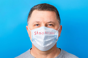 Portrait of man wearing medical mask Stay home at blue background. Coronavirus self isolation concept. Respiratory protection