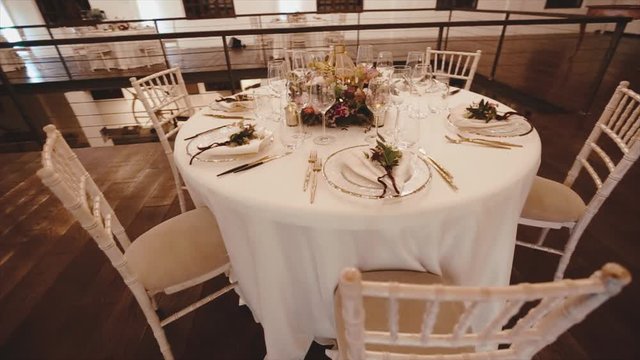 Whirl top filming of table serving, floral decoration and chiavari chairs in the fashionable authentic luxury restaurant