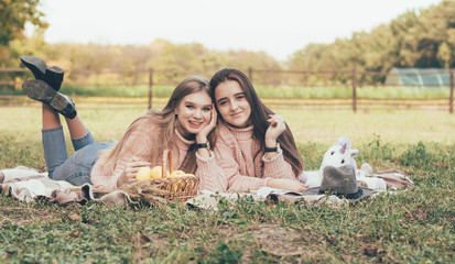  Girlfriends relax outdoors lying on a plaid in identical sweaters