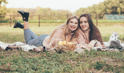  Girlfriends relax outdoors lying on a plaid in identical sweaters