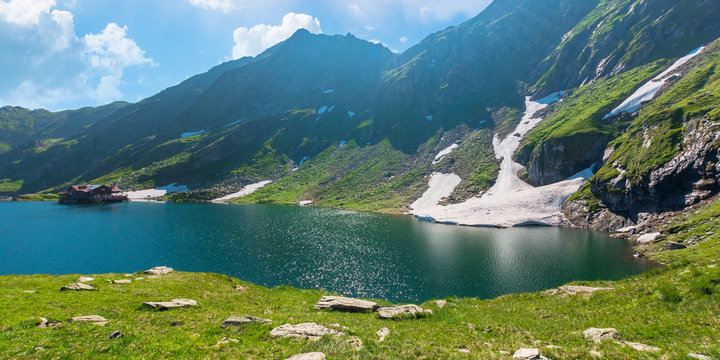 beautiful nature of romania mountains. lake balea in the valley. hills covered in grass, rocks and snow. wonderful summer sunny day with gorgeous cloudscape