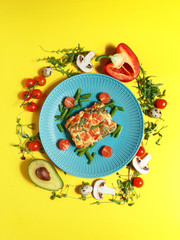 Culinary dishes made from natural products on a colored plate on a background with ingredients for cooking. Healthy eating concept. Top view.