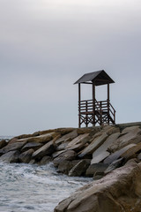 Lonely gazebo by the sea in cloudy rainy weather. Winter cold sea. Sad mood and despair.
