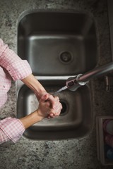 Obraz premium Young woman washing her hands at the kitchen sink