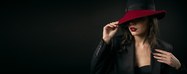 Elegant fashionable woman hiding face beneath hat touching brim and jacket, retro style, copyspace