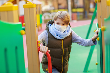 School boy wearing medical mask, on a playground