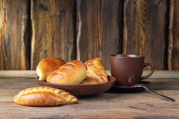 plate with fresh hot mini pies and coffee cup on wooden table, close view 