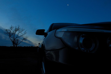 Scheinwerfer vom Auto vor Sonnenaufgang, blauer Himmel