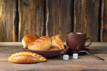 plate with fresh hot mini pies and coffee cup on wooden table, close view 