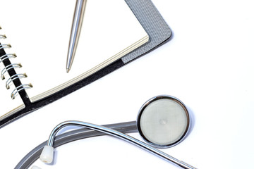 Medical stethoscope, notebook, pen on a white background
