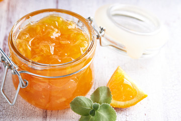 Homemade orange jam in jar on a white table. Food background Copy space