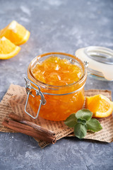 Homemade orange jam in jar on a gray table. Food background Copy space