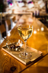 A photo of a light yellow transparent cocktail in a nick and nora glass, served on a small tray with garnish in a small glass bowl