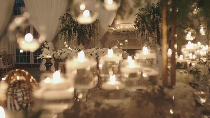 Pompous floral decoration of wedding hall for the celebration, lots of burning candles in the decorated with flowers room in the evening