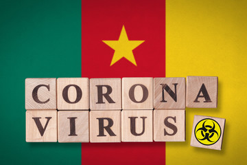 Cameroon flag background and wooden blocks with letters spelling CORONAVIRUS and quarantine symbol on it. Novel Coronavirus (2019-nCoV) concept, for an outbreak occurs in Cameroon.