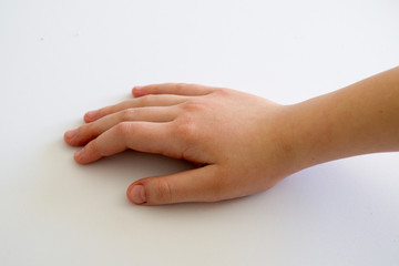 child's hand lies on a white table