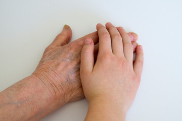 hand of an old woman and a hand of a child on a white background