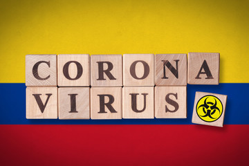 Colombia flag background and wooden blocks with letters spelling CORONAVIRUS and quarantine symbol on it. Novel Coronavirus (2019-nCoV) concept, for an outbreak occurs in Colombia.